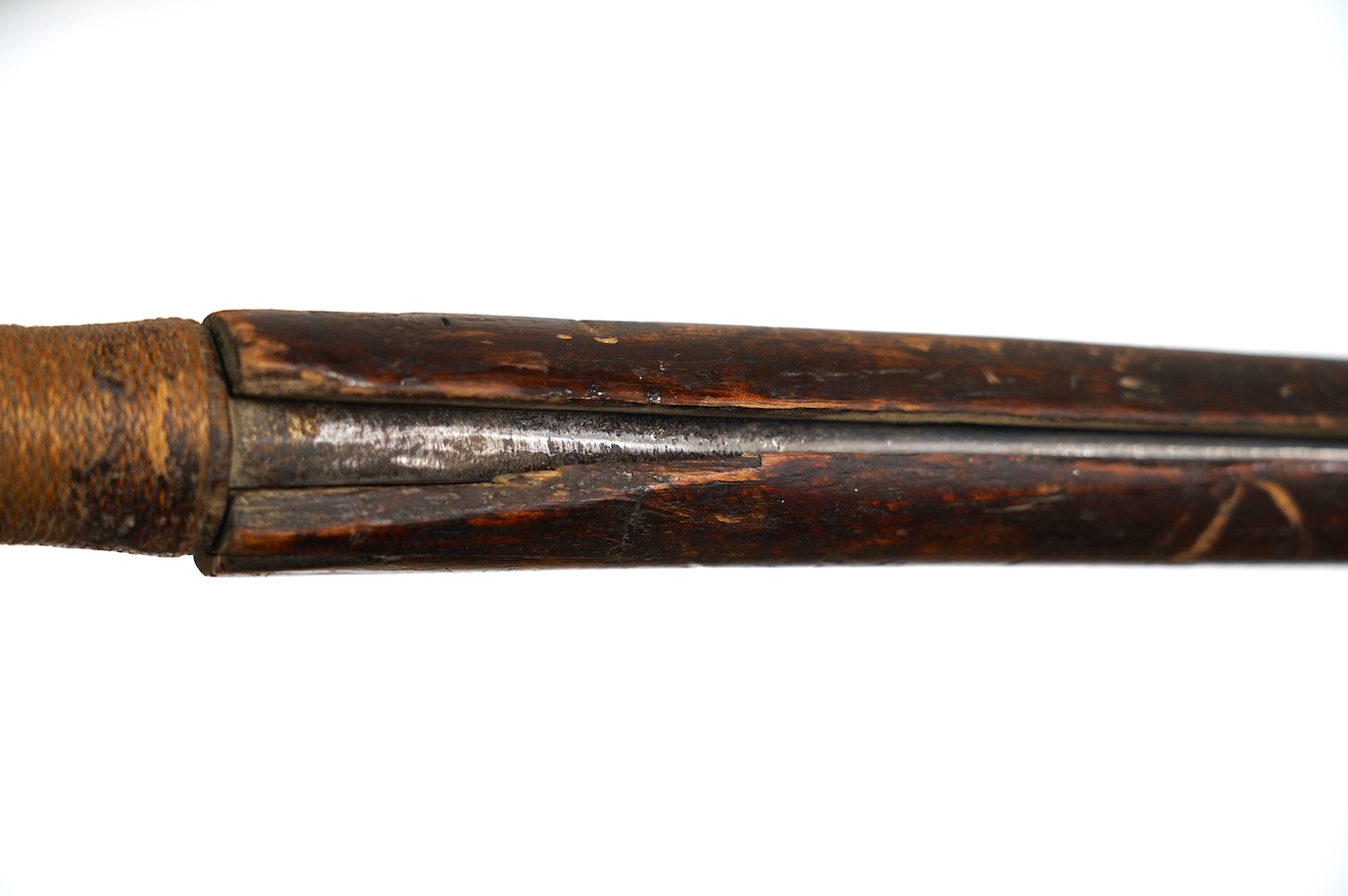 A Burmese sword Dha, curved single edge blade, hilt bound with platted rattan, in its wooden scabbard, blade 60cm. Condition - fair